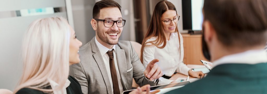 ein Mann im Anzug mit Brille spricht zu drei Kollegen