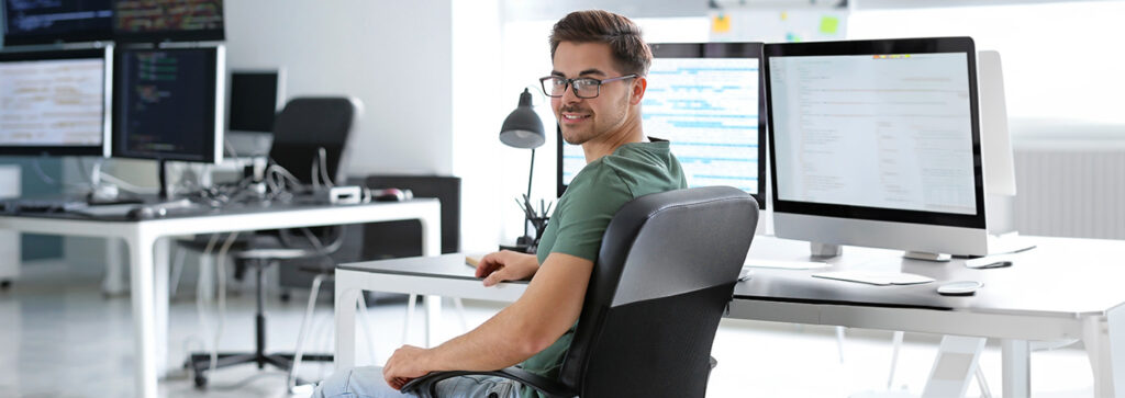 ein junger Mann sitzt in einem hellen, modernen Büro am Schreibtisch