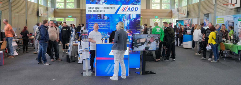 Viele Menschen unterhalten sich an Messeständen in der Sporthalle