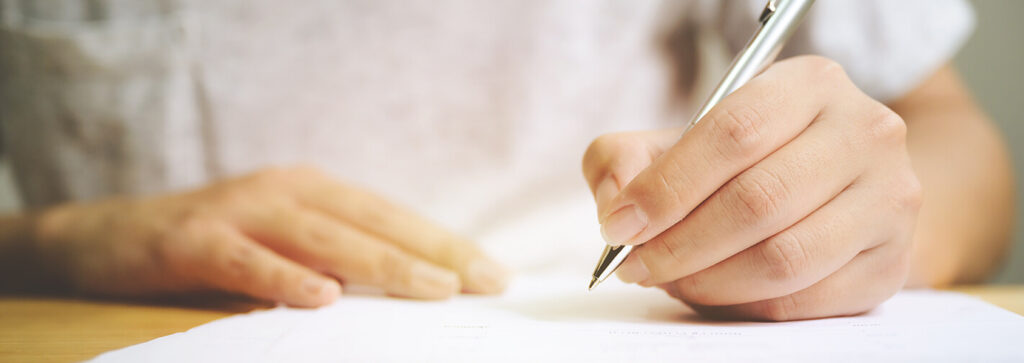 Eine Hand hält einen Stift über einem Blatt Papier