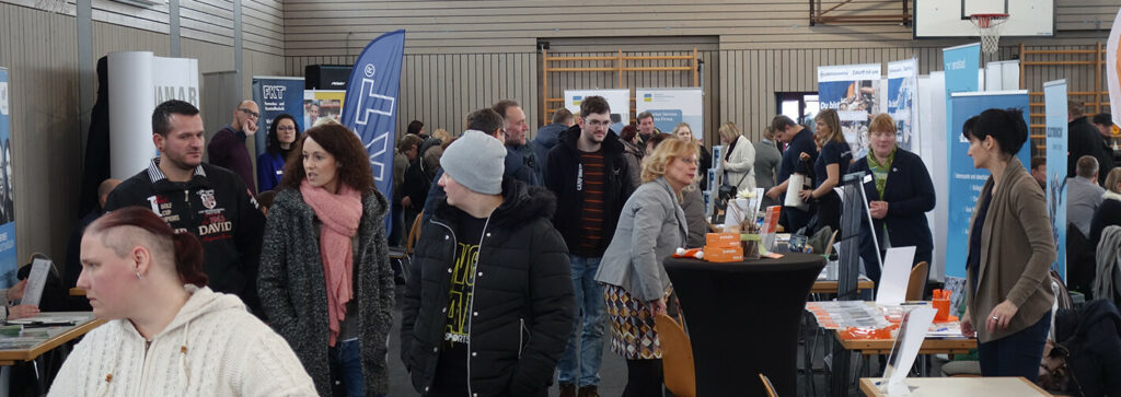 Messestände und Umschüler zur Jobmesse in der Sporthalle