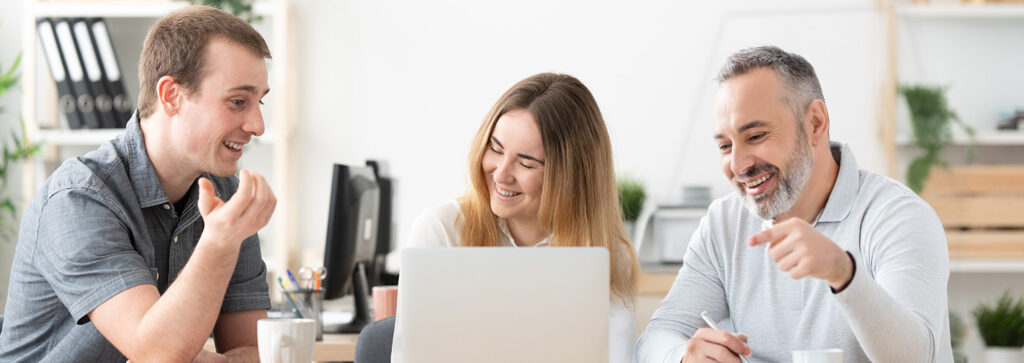 Drei Personen schauen gemeinsam auf einen Laptop