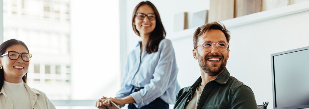 Drei junge Menschen lachen gemeinsam im Büro
