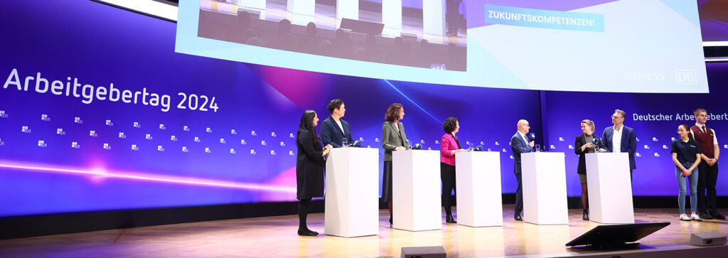 Menschen stehen auf der Bühne zum Arbeitgebertag 2024