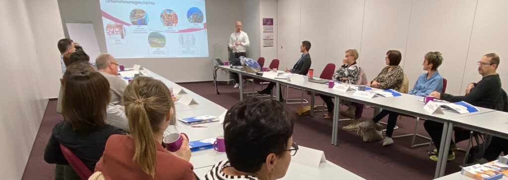 Menschen sitzen an langen Tischen im Meetingraum