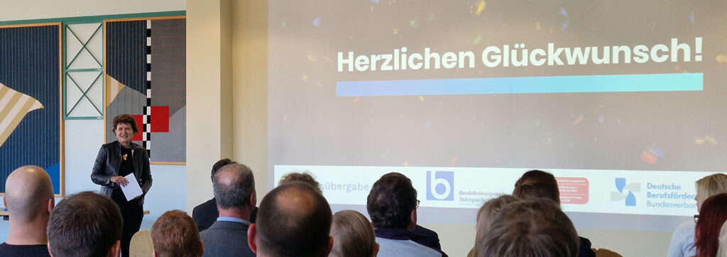 Eine Frau begrüßt die Absolventen im BFW Thüringen