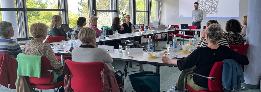 Personen sitzen im Meetingraum und hören dem Referenten zu