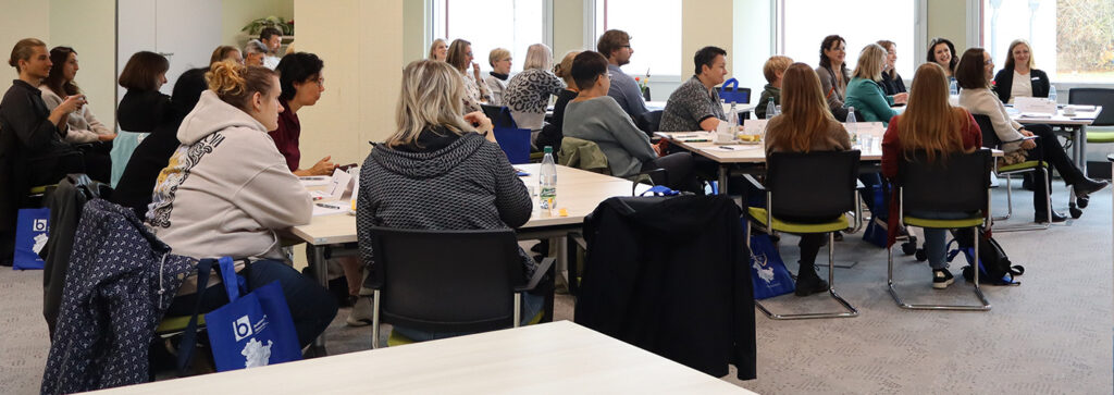 Eine Gruppe Menschen in einem Raum hören aufmerksam zu.